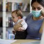 Worried mother with face protective mask working from home